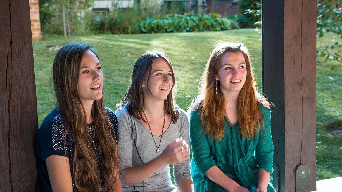 Three students sitting in a row outside